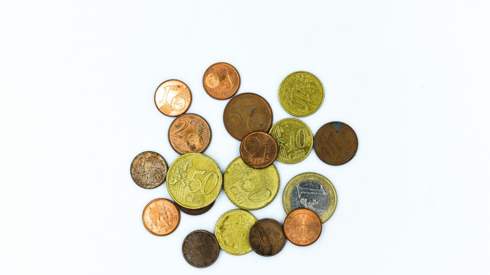 Scattered euro coins of copper and gold tones on a clean white surface
