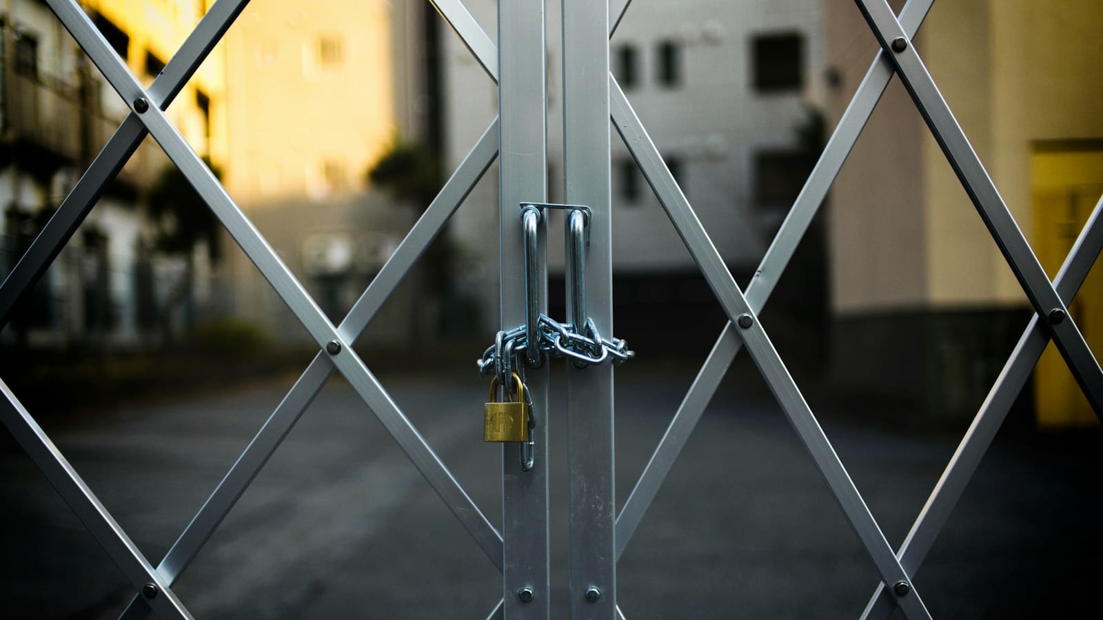 Folding steel security gate closed with a chain and brass padlock