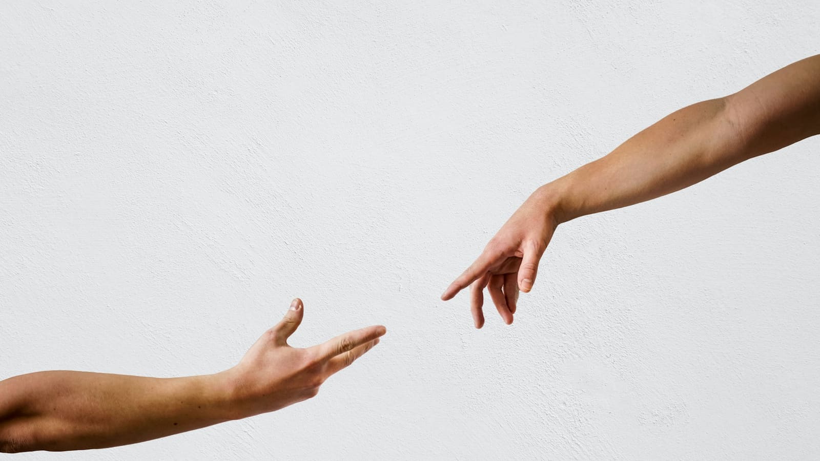 Two outstretched hands reaching toward each other against a plain white wall