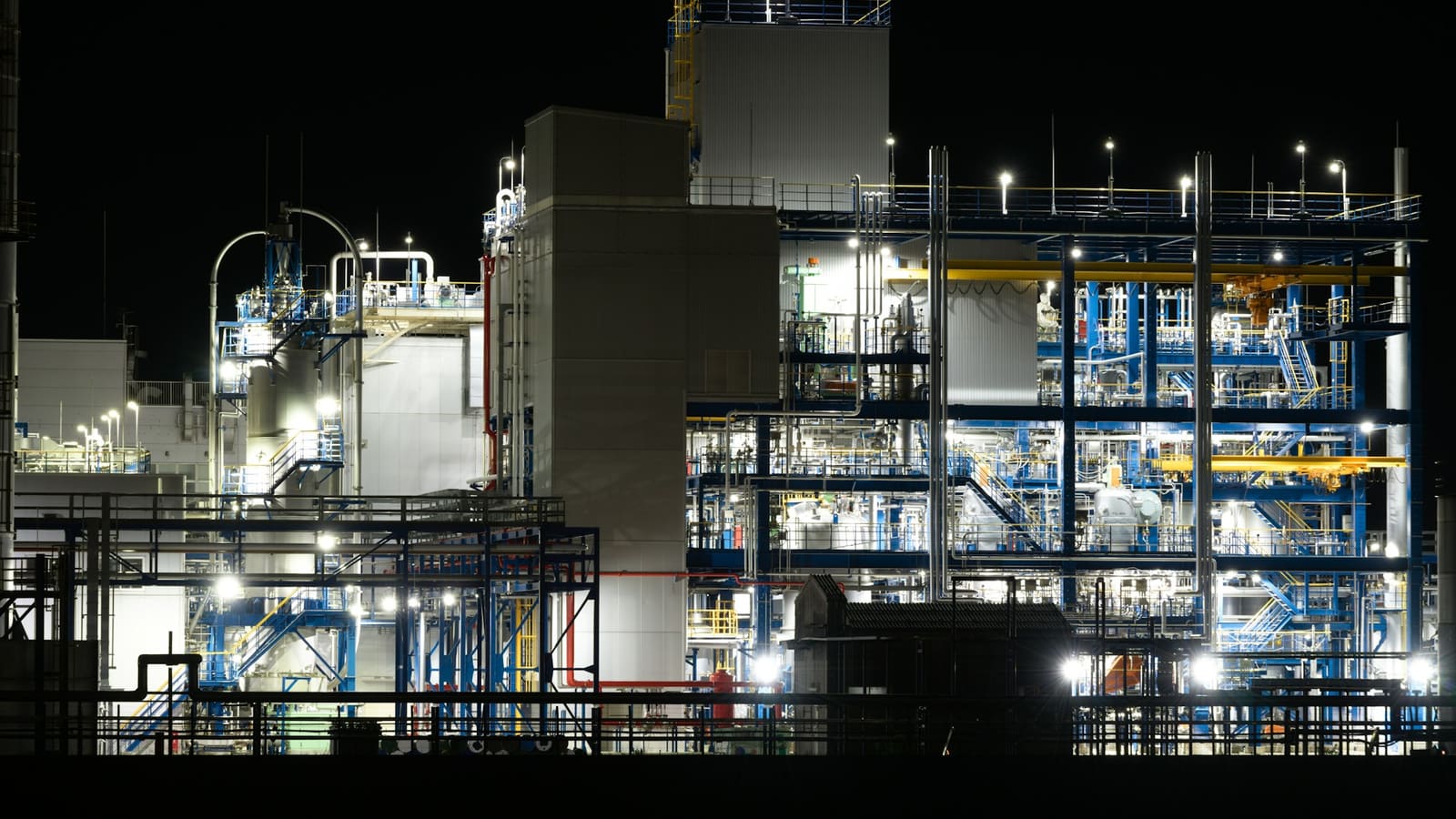 An industrial plant lit at night, with steel structures, pipework and walkways