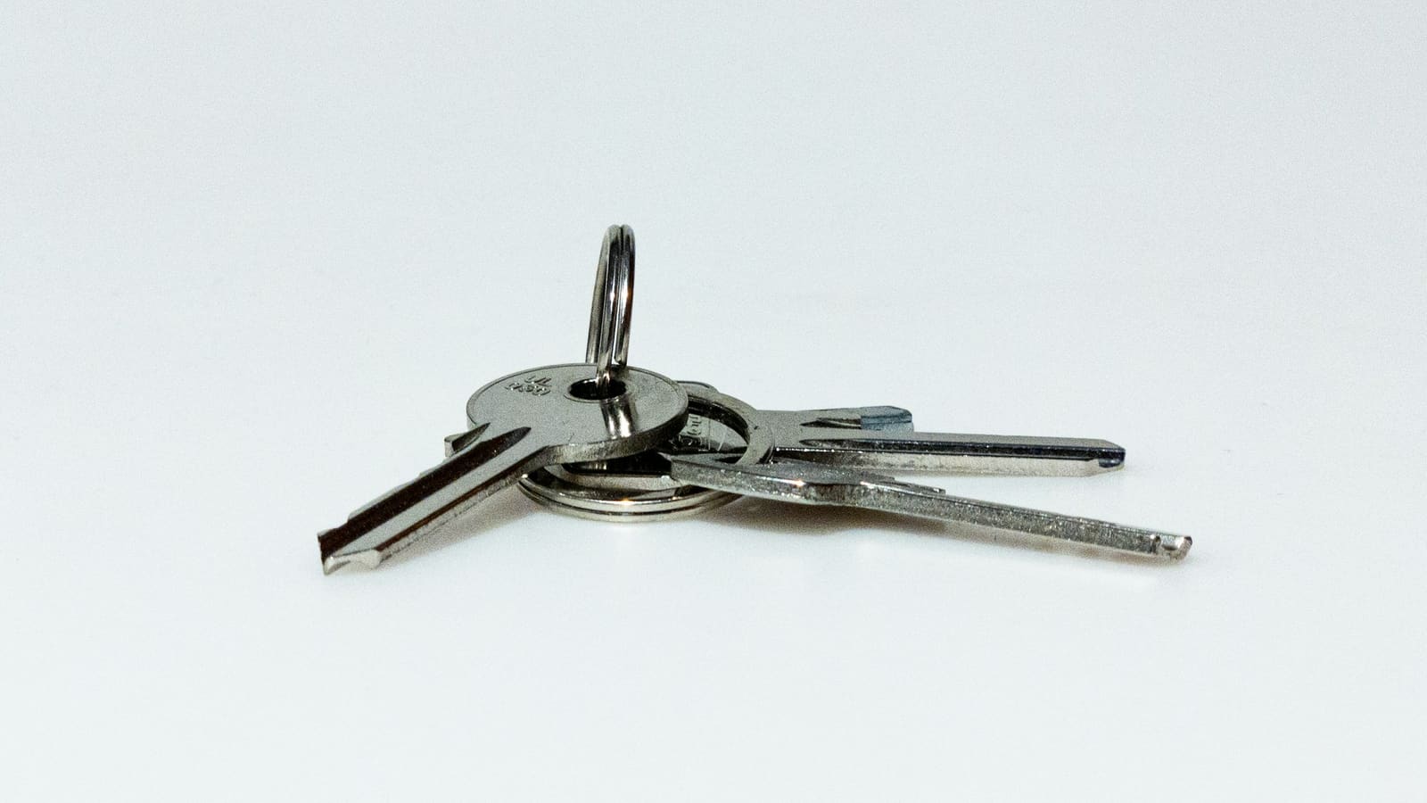 Three silver keys on a split ring fanned out against a plain white background