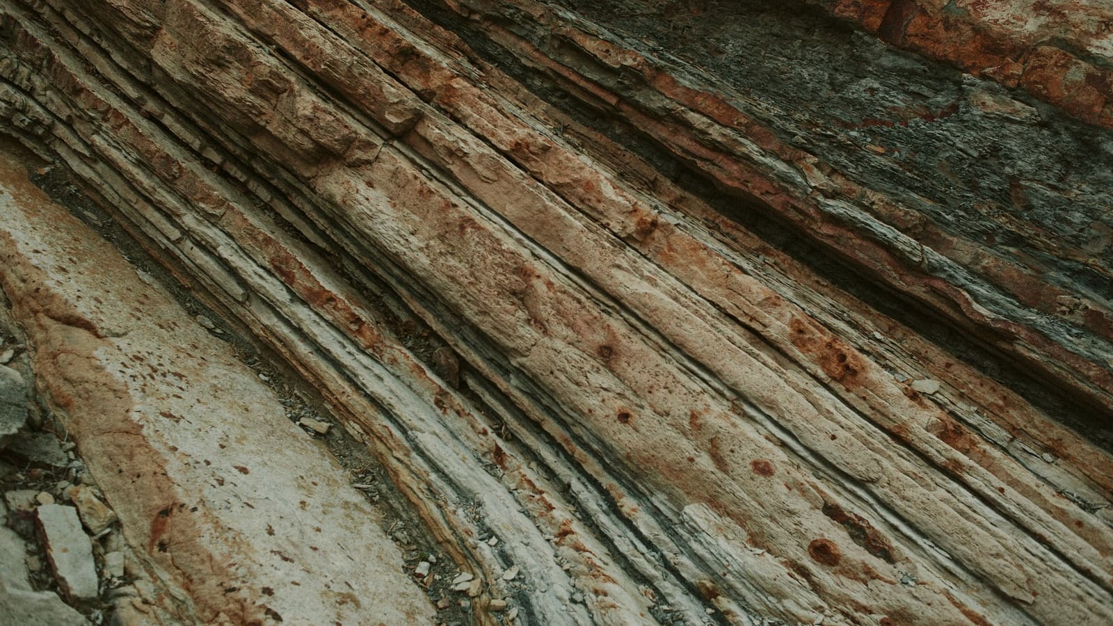 Close-up of diagonal rock strata with many stacked layers in rust and grey tones