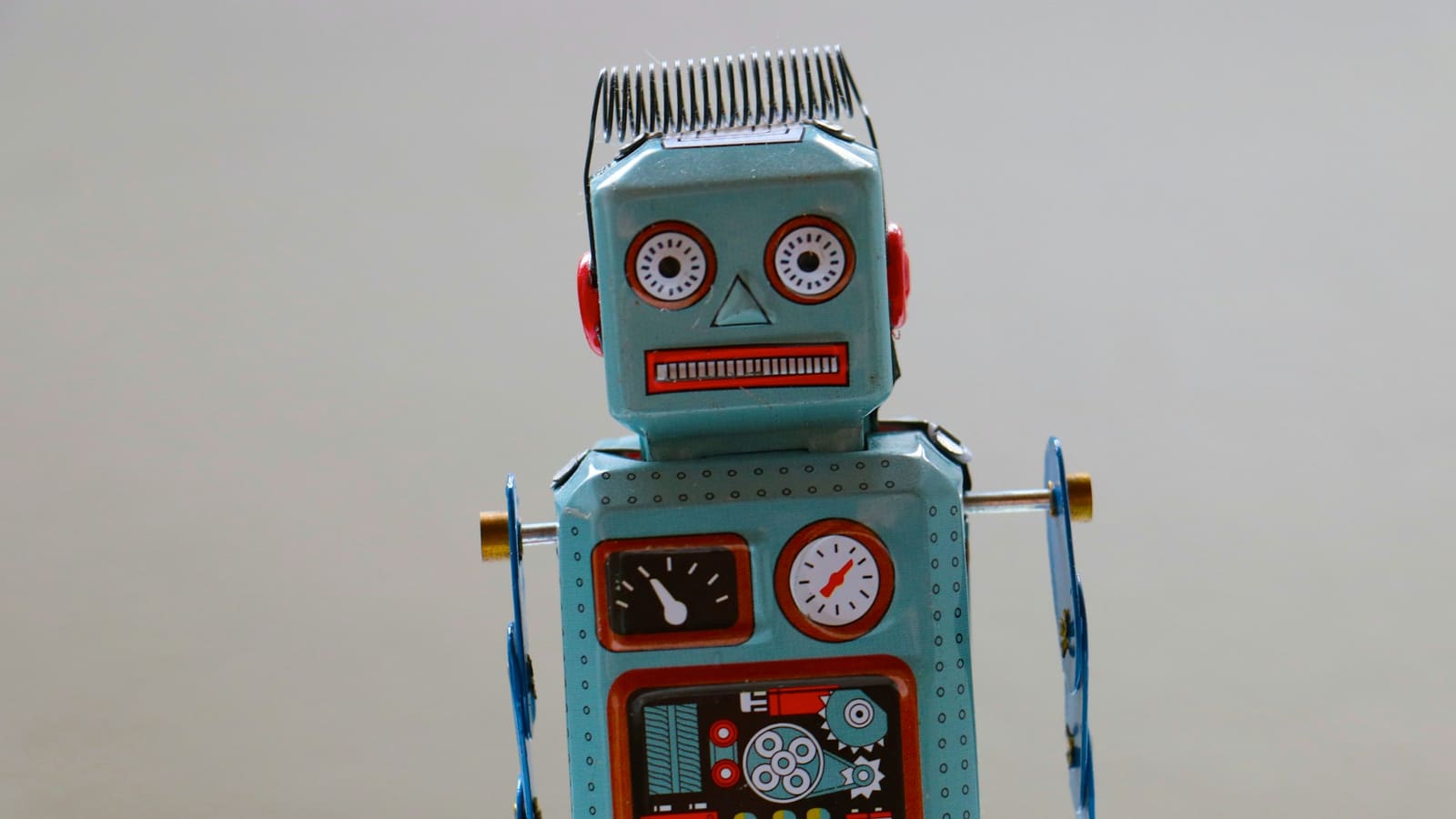 Close up of a blue vintage tin toy robot against a soft grey background